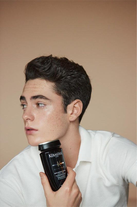 Hombre sosteniendo el shampoo Kérastase Densifique Bain Densité Homme